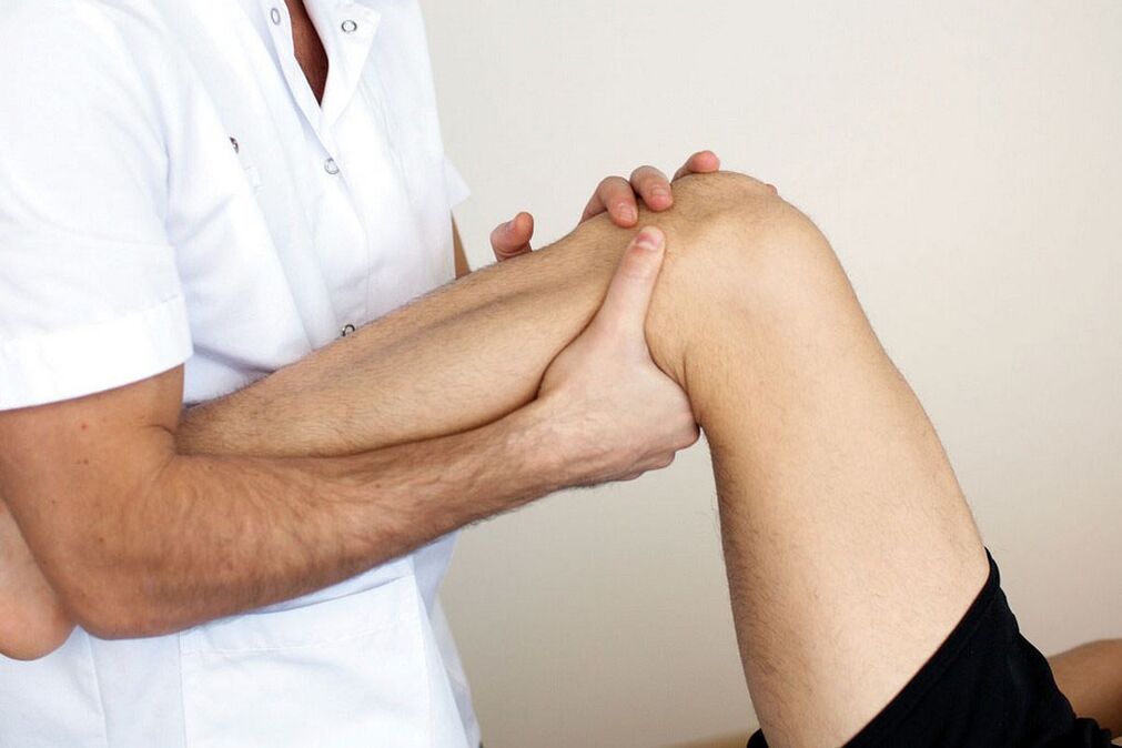 lekarz badający kolano z artrozą